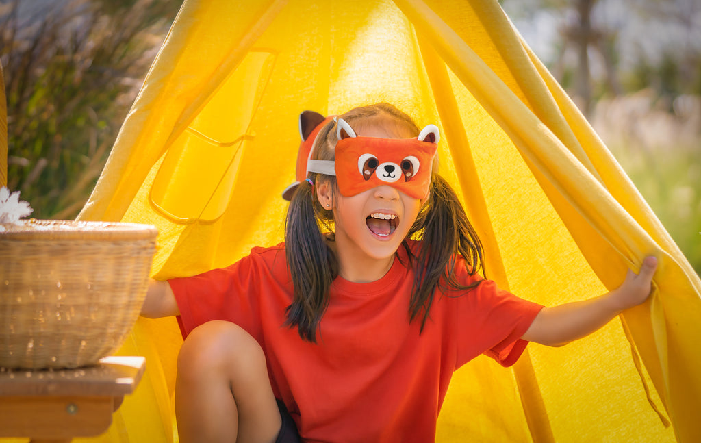 girl laughing in yellow tent wearing ru the red panda travel pillow